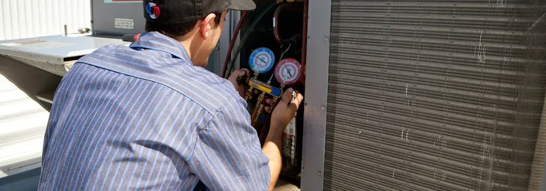 HVAC technician servicing a condenser unit in Mesquite